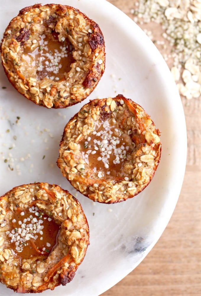 three mini muffins on a white plate with some oats in the background