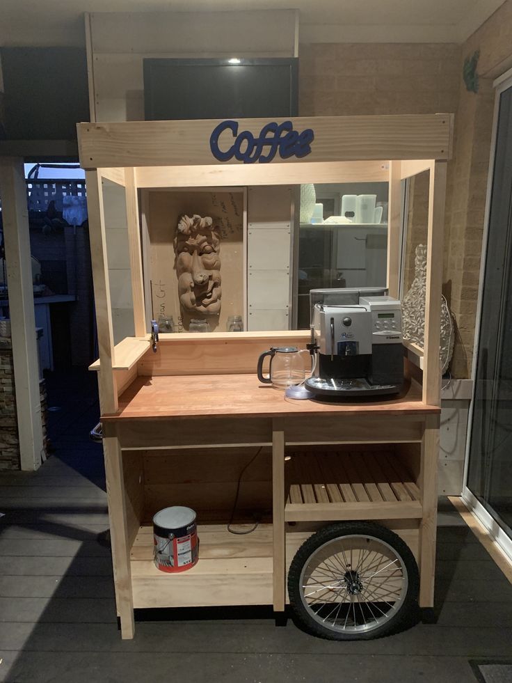 the coffee cart is made out of wood and has a bike tire in front of it