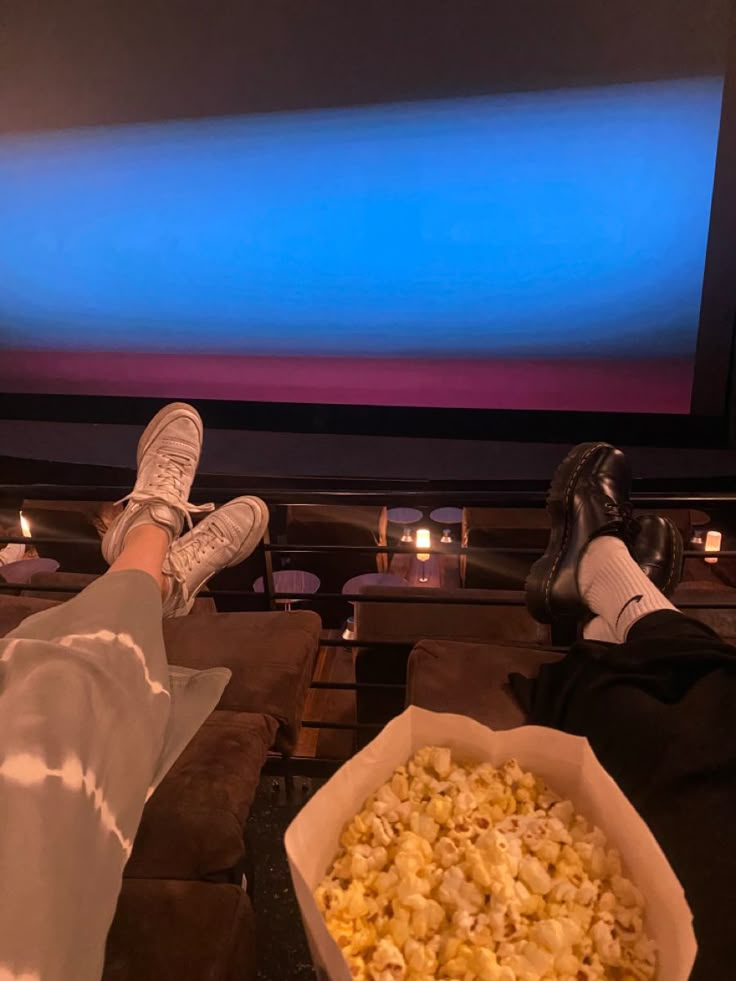 someone's feet in front of a television watching movies with their feet propped up on the screen