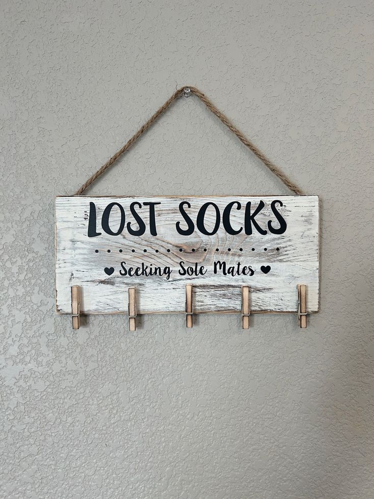 a wooden sign hanging on the wall that says lost socks seeking sole maties with clothes pins attached to it