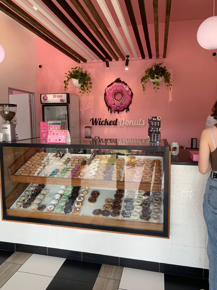 a woman standing in front of a donut shop with her hand on the counter