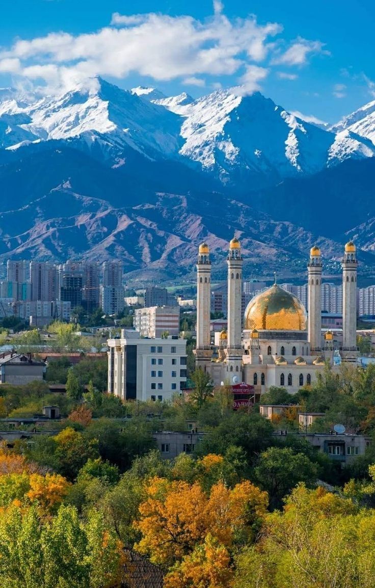 the city with mountains in the background and snow - capped mountains in the foreground