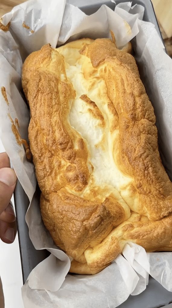 a person is holding a loaf of bread in a box with wax paper on it