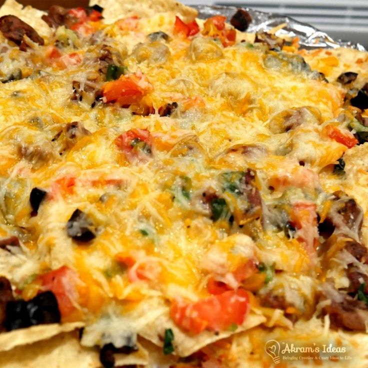 a close up of a plate of nachos with cheese and black olives