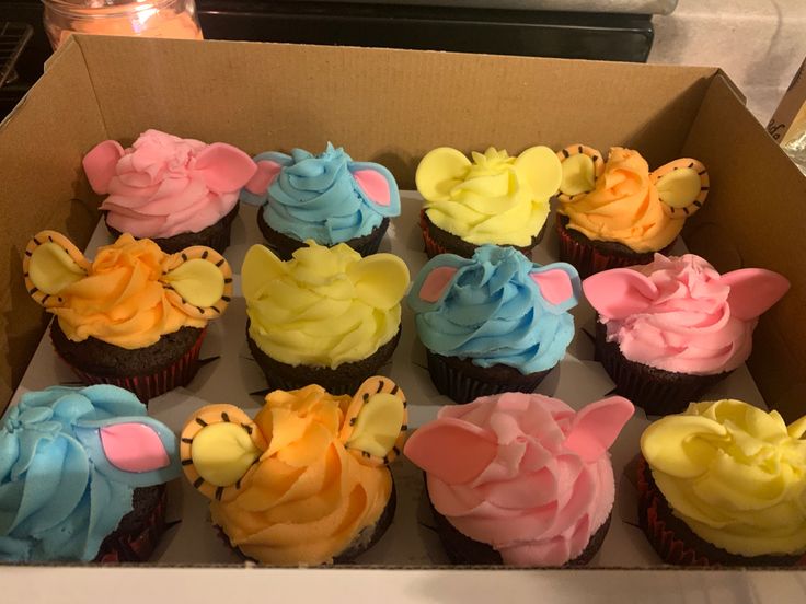 a box filled with lots of colorful cupcakes on top of a countertop