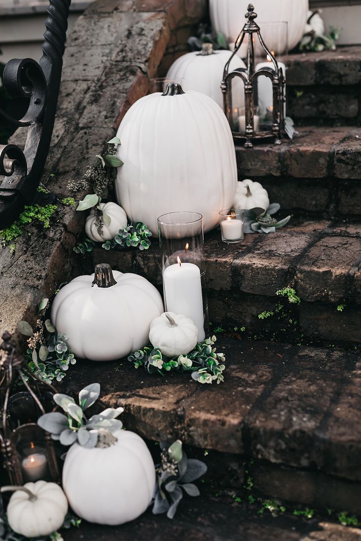 white pumpkins and greenery on steps with candles