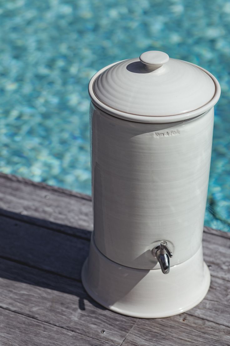 a white container sitting on top of a wooden deck next to a swimming pool