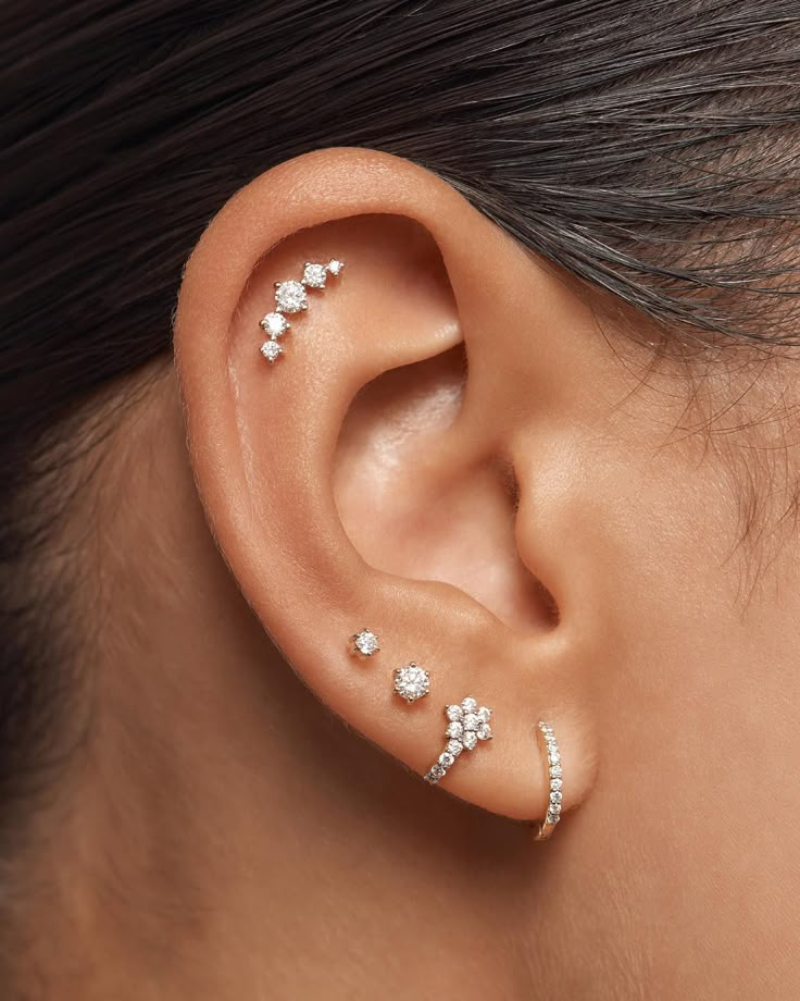 a woman's ear with three different piercings