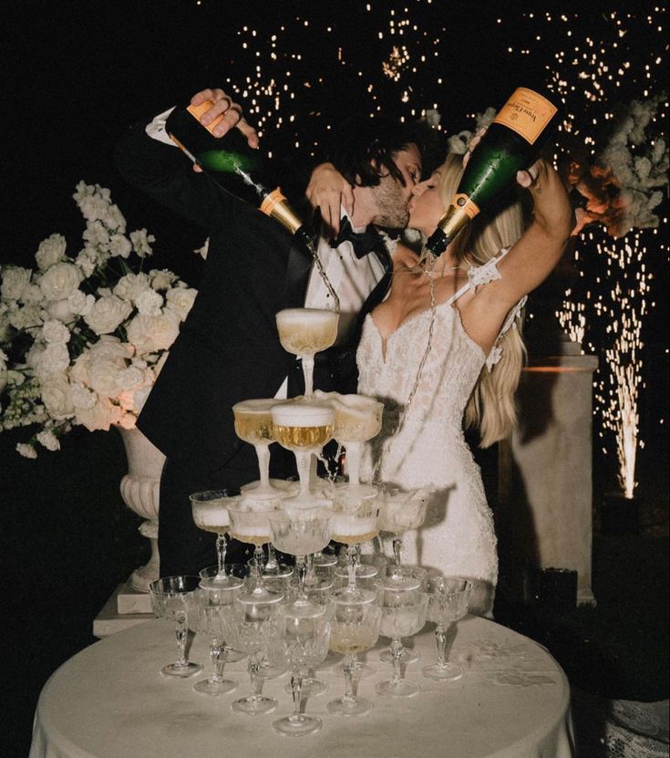 a newly married couple standing next to each other in front of champagne flutes