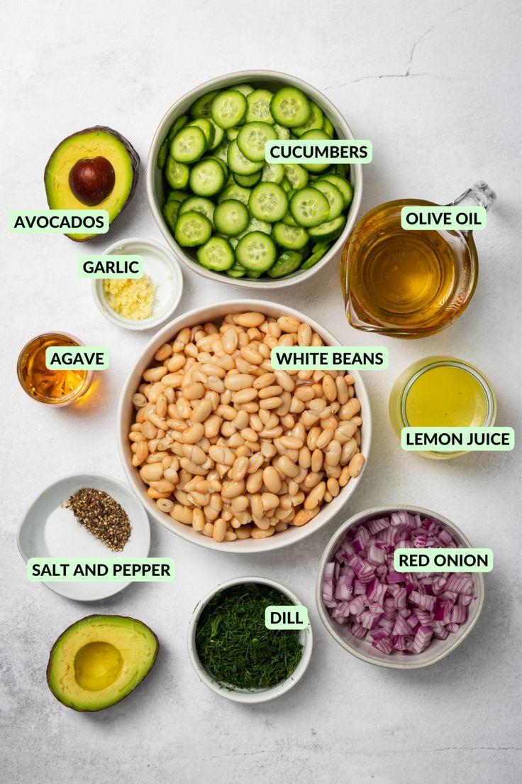 the ingredients for an avocado salad laid out in bowls on a white surface