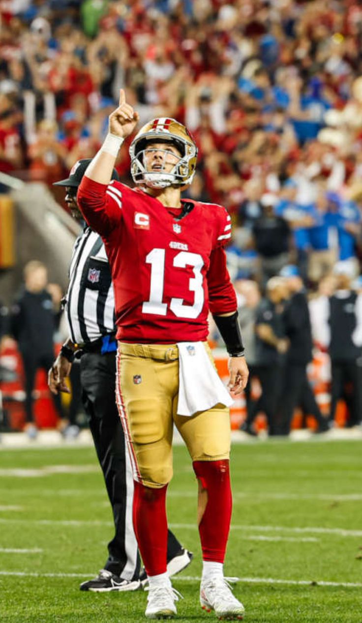 a football player is giving the thumbs up sign on the field with his arm in the air