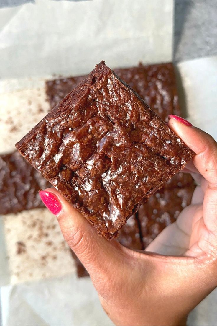 a person holding up a chocolate brownie in their hand