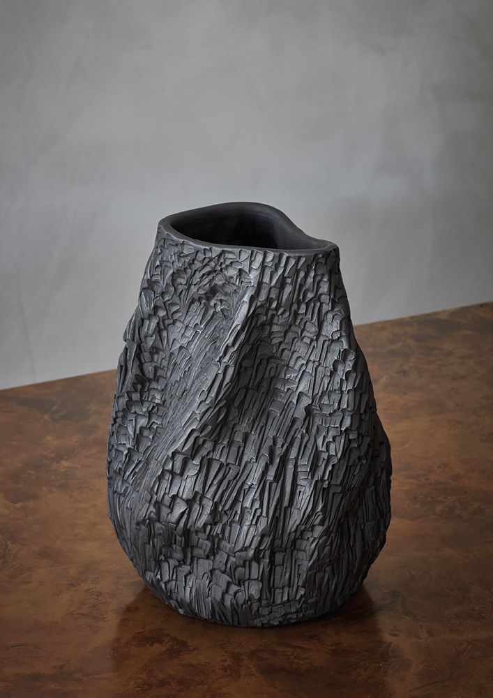 a black vase sitting on top of a wooden table