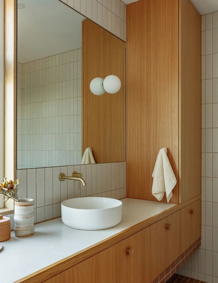 a bathroom sink sitting under a mirror next to a wooden cabinet and white counter top