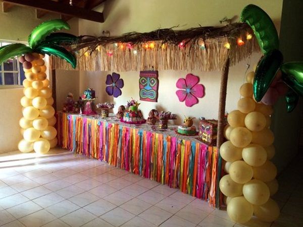 a table with balloons, streamers and palm trees on the wall in front of it