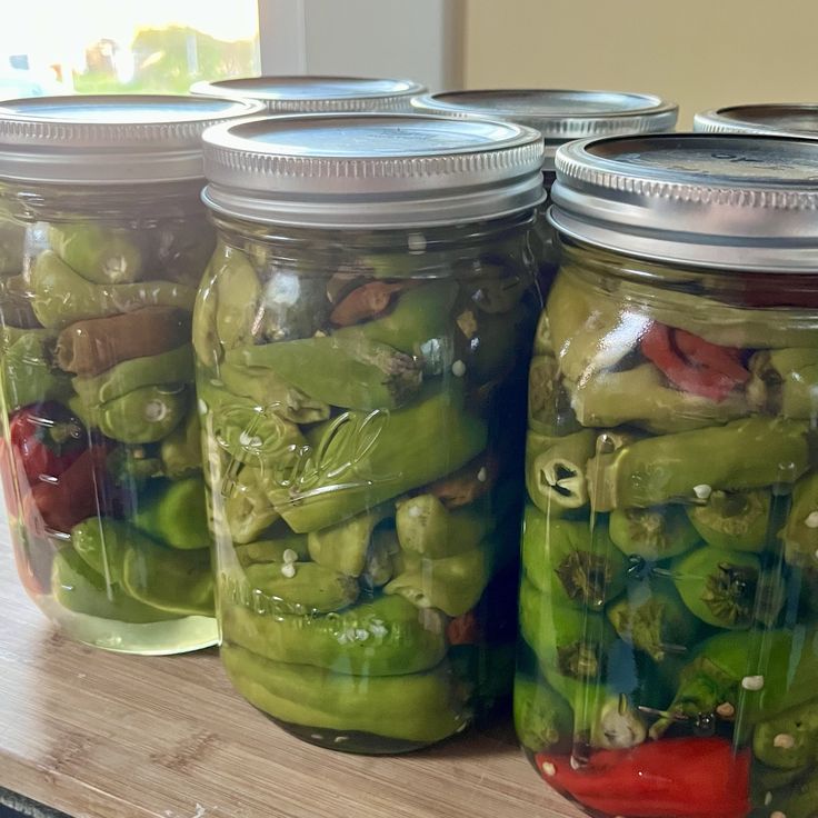 several jars filled with pickles on top of a wooden table