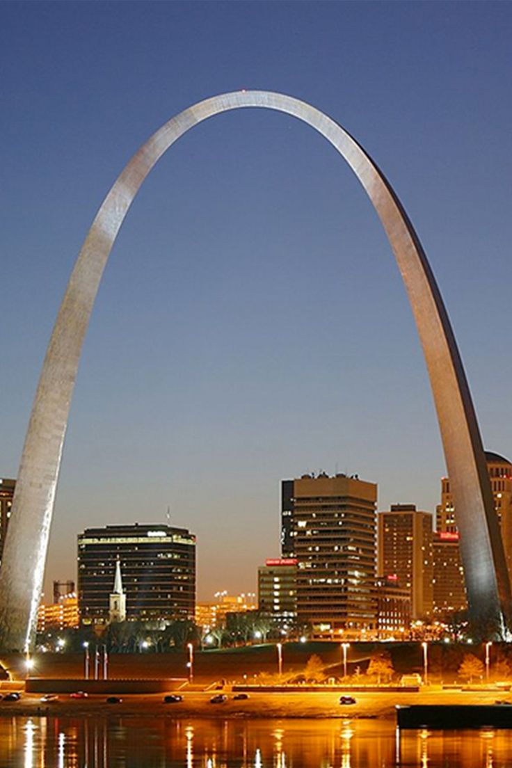 the st louis arch is lit up at night in front of the city's skyline