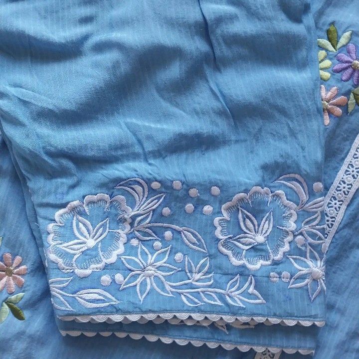 an embroidered piece of cloth with flowers and lace on the edge is laying on its side