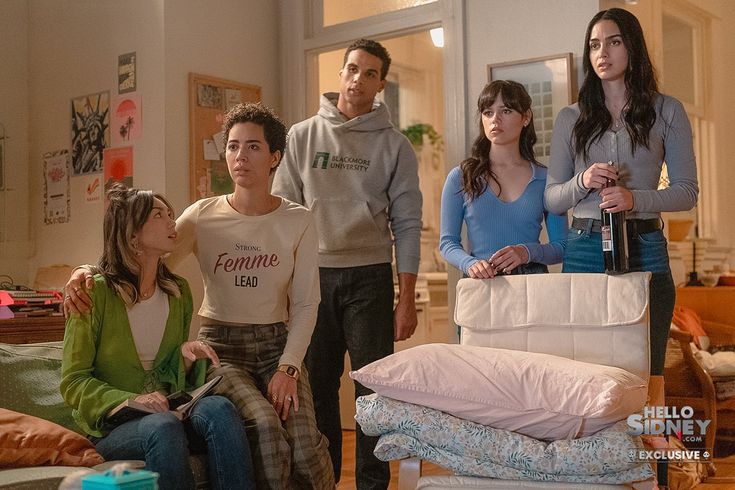 a group of young people standing in a living room next to each other and looking at the camera