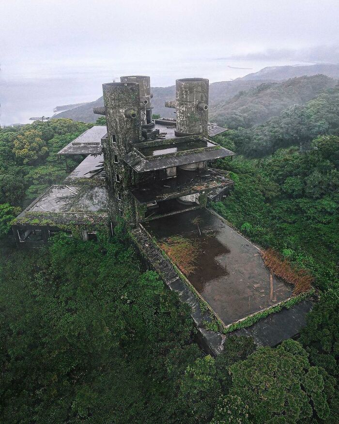 an abandoned building surrounded by lush green trees