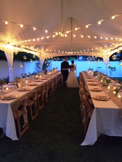 a couple is standing under a tent with tables and chairs set up for their wedding reception