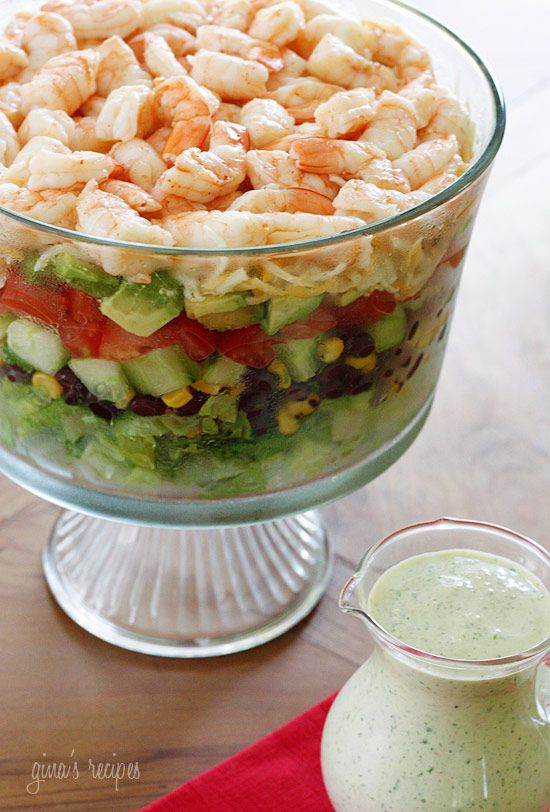 a salad with shrimp and lettuce is in a glass bowl on the table