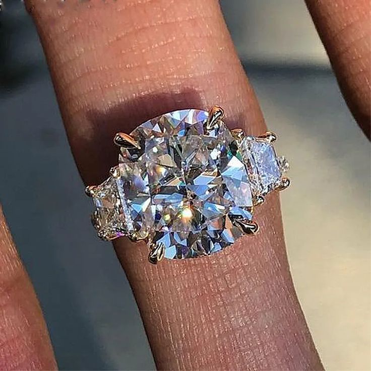 a woman's hand holding a diamond ring with three stones on the middle and sides