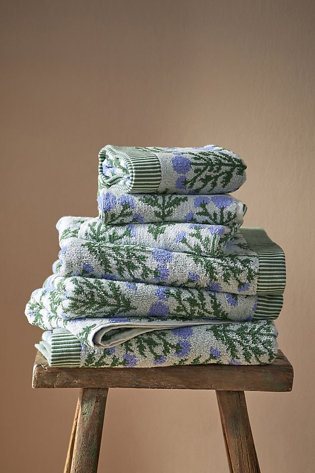 stack of folded towels sitting on top of a wooden stool