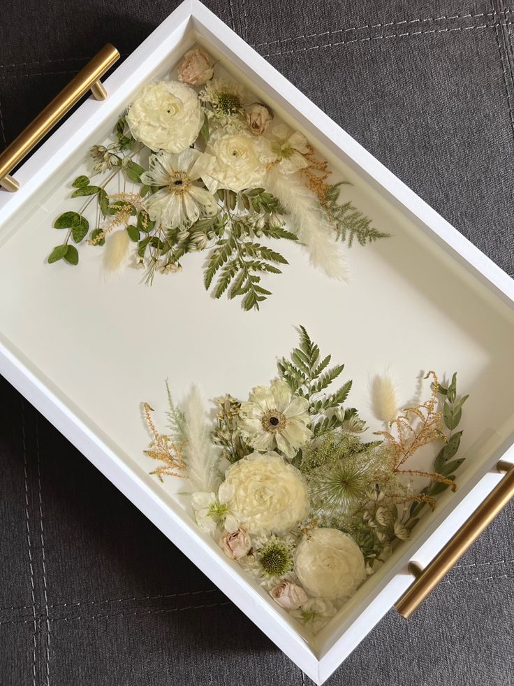 a white tray with flowers and leaves on it