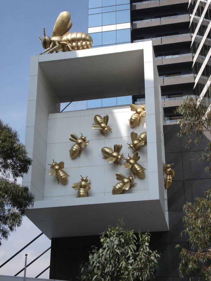 some gold bees are on the side of a white wall in front of a tall building