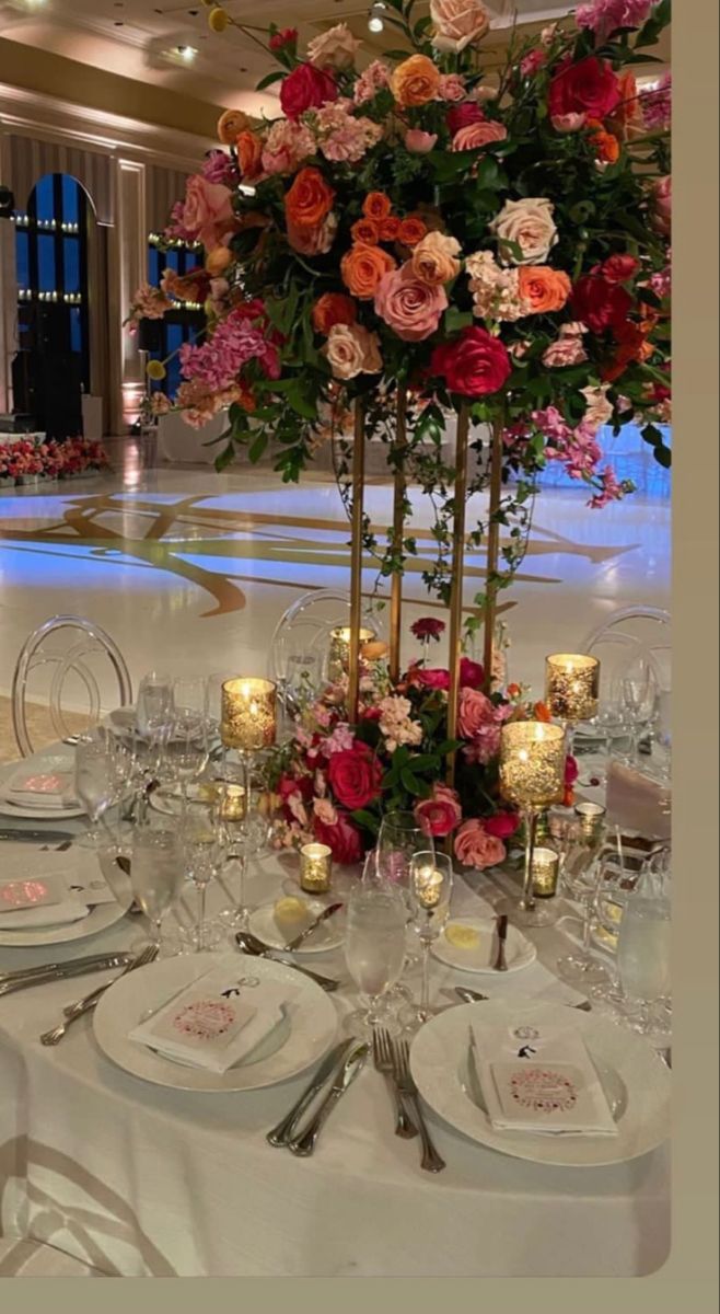 the table is set with flowers, candles and place settings for an elegant wedding reception