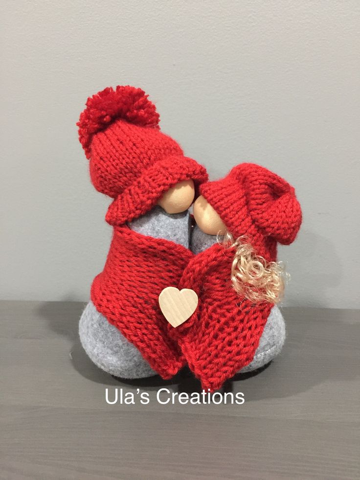 a knitted doll with a red coat and heart on it's chest sitting on a table