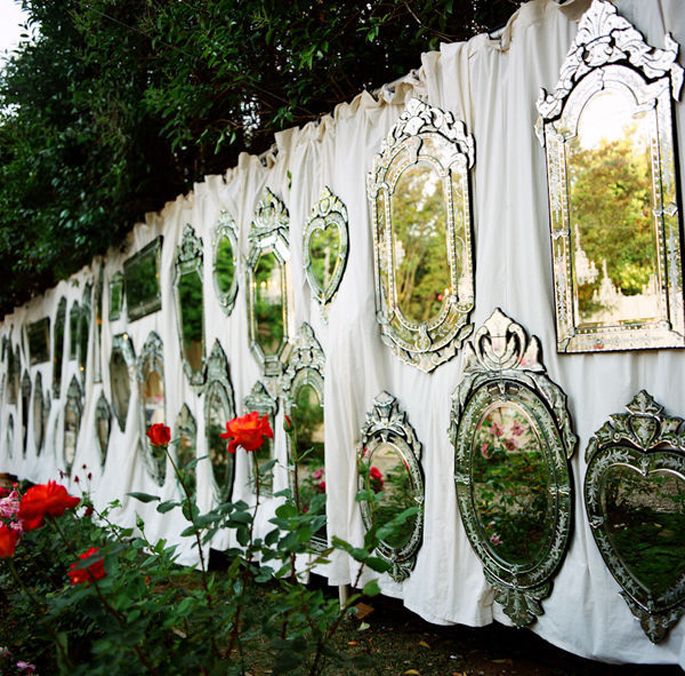 there are many mirrors on the wall and some flowers in front of them, along with roses