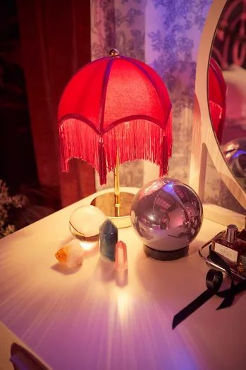 a red lamp sitting on top of a table next to a mirror and other items