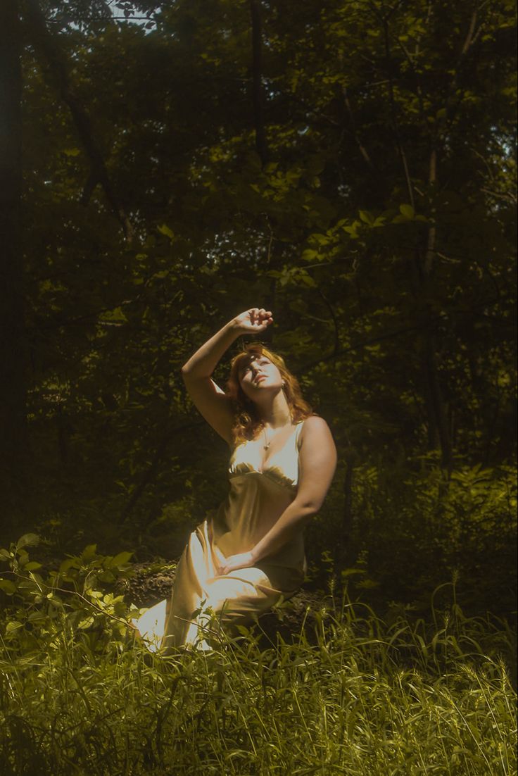 a woman sitting in the grass with her hands on her head