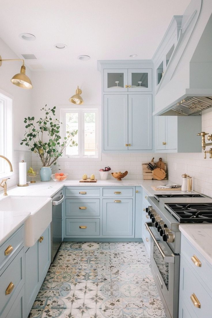 a kitchen with light blue cabinets and gold pulls on the handles, along with white counter tops