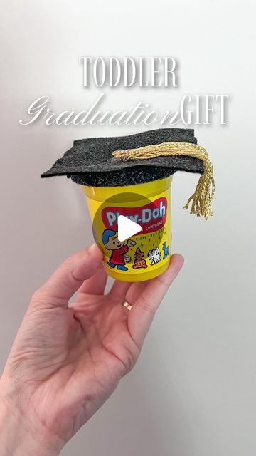 a hand holding a cup with a graduation cap on it and the words toddler graduation gift