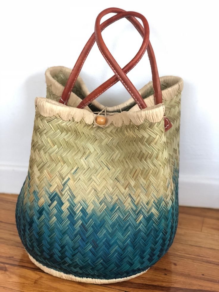 These beautiful pieces are designed in South Africa. Handmade with raffia and featuring leather handles, these bags bring the perfect mix of bohemian chic to everyday wear! Capable of being used as a handbag, basket or storage-this multi-purpose piece is a cannot miss! The double closure top provides a multi-style capability as well! Sizing: 16 inches wide x 12 inches deep x 13 inches high Bohemian Natural Bucket Bag For Daily Use, Palm Leaf Straw Bag With Bamboo Handle, Bohemian Bucket Bag With Leather Handles For Vacation, Bohemian Straw Bag With Double Handle, Bohemian Double Handle Bucket Bag For Beach, Brown Bohemian Bucket Bag, Bohemian Crochet Bucket Bag With Leather Handles, Everyday Bohemian Woven Bucket Bag, Blue Handwoven Bucket Bag