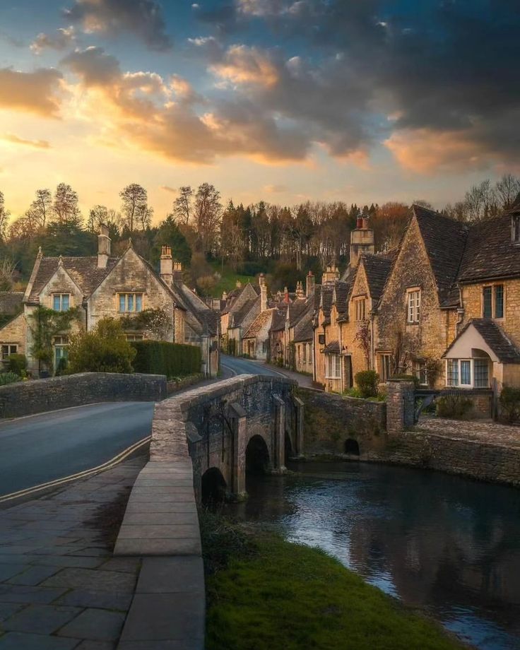 a river running through a small village next to a bridge with houses on the other side