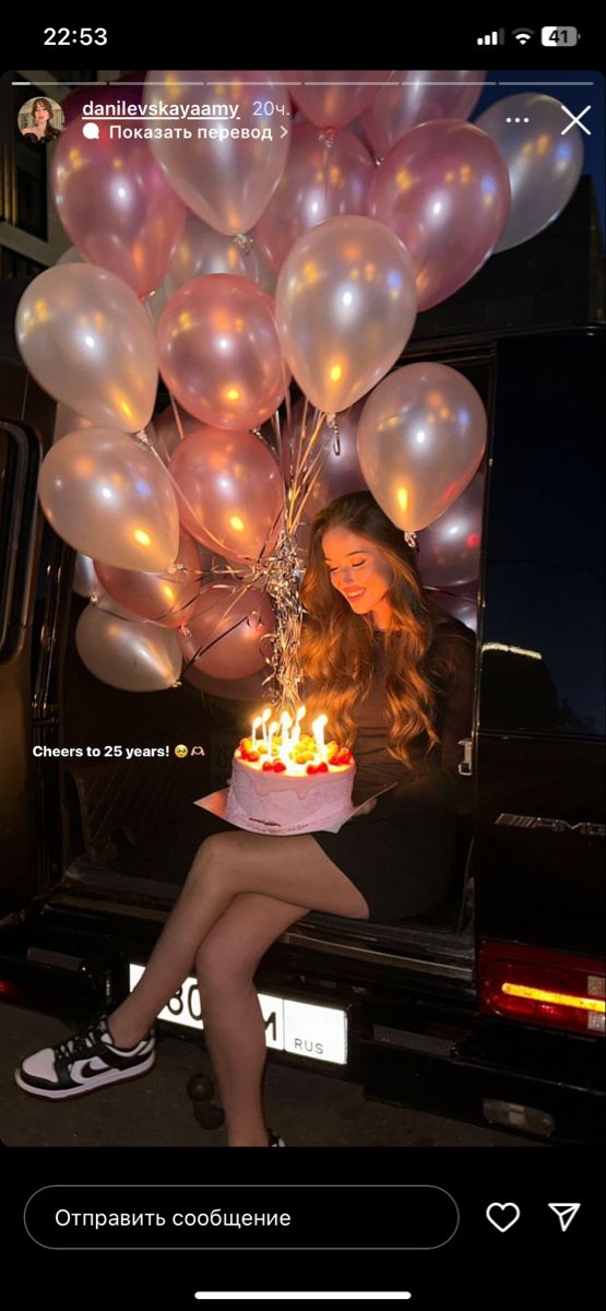 a woman sitting in the back of a truck holding a cake with candles on it