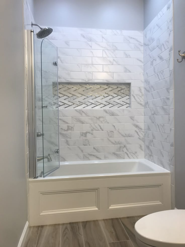 a bathroom with white tile and wood flooring on the walls, along with a walk in shower