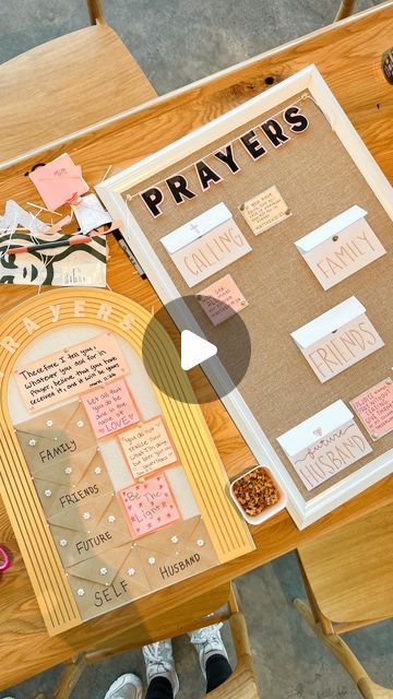 a person sitting at a wooden table with papers and scissors on it, next to a sign that says pray