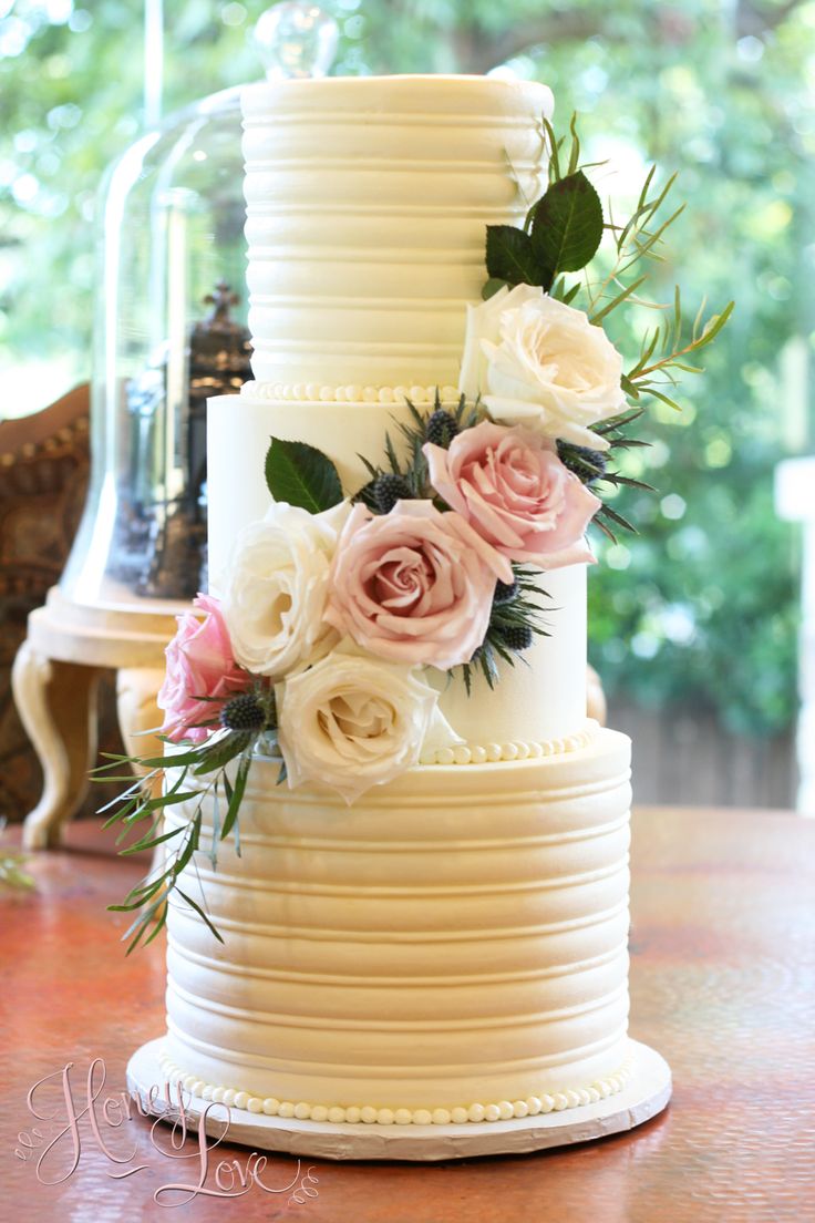 a three tiered white wedding cake with pink and white flowers