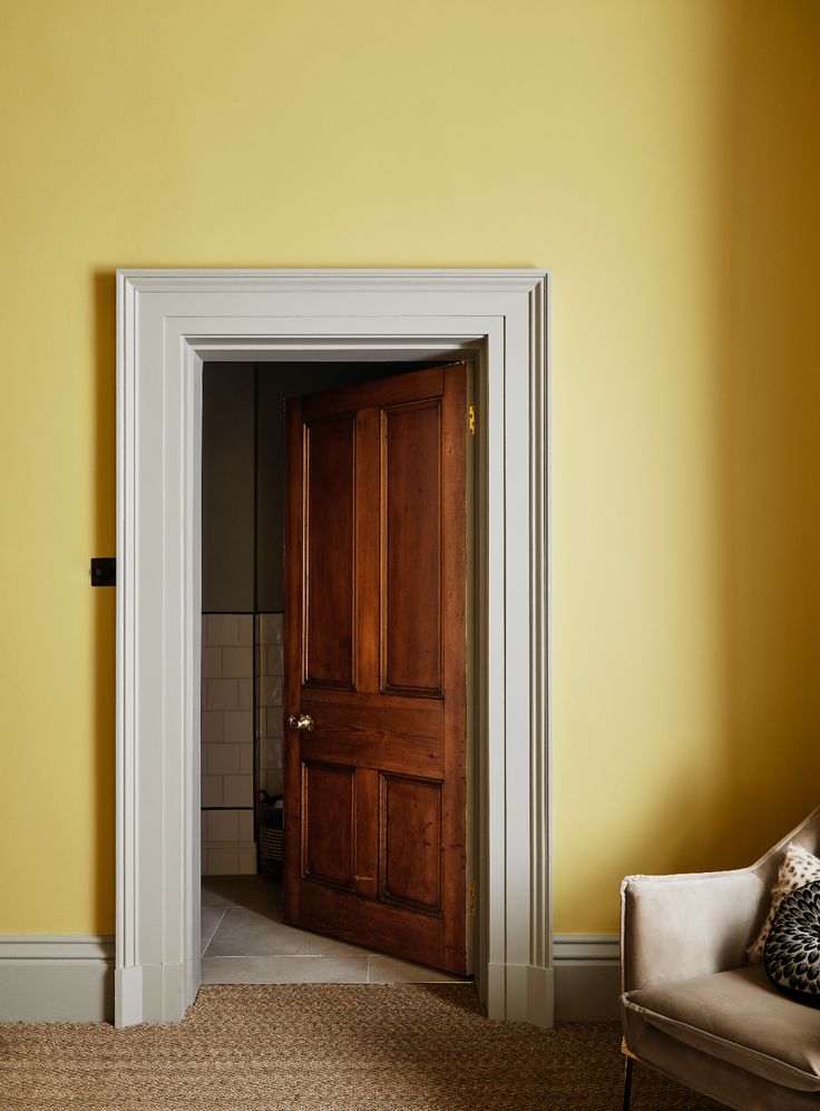 an open door in a yellow room with a chair