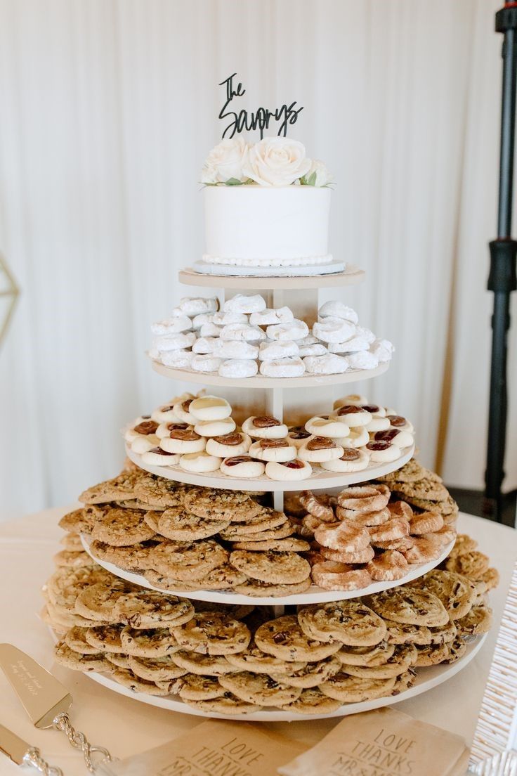 a three tiered cake and cookies on a table