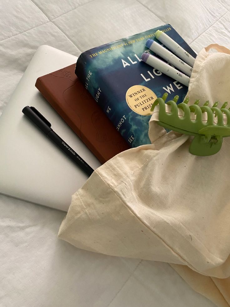 a book, pencils, and an alligator on a white table cloth with a laptop