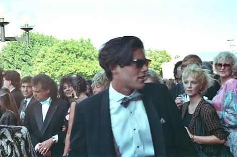 a man in a tuxedo and bow tie walking through a crowd