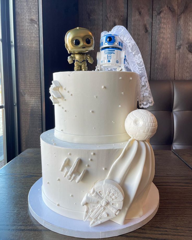 a star wars themed wedding cake with a robot figurine on the top tier