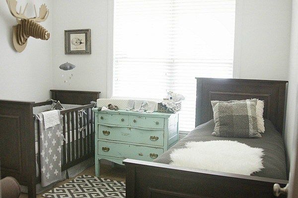 a baby's room with a crib, dresser and deer head on the wall