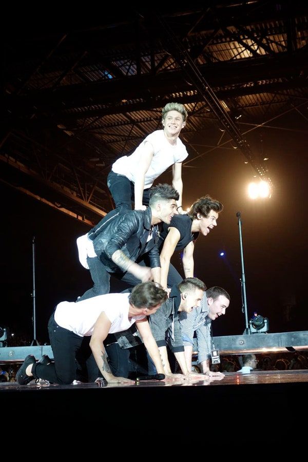 a group of people standing on top of each other in front of a stage with lights